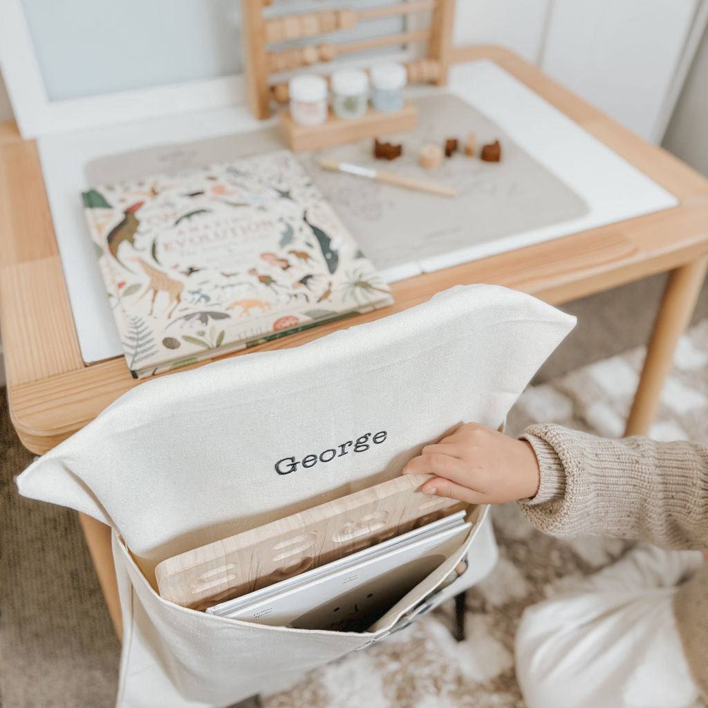 Personalised chair bag in blue gingham on a child's chair with custom embroidery.