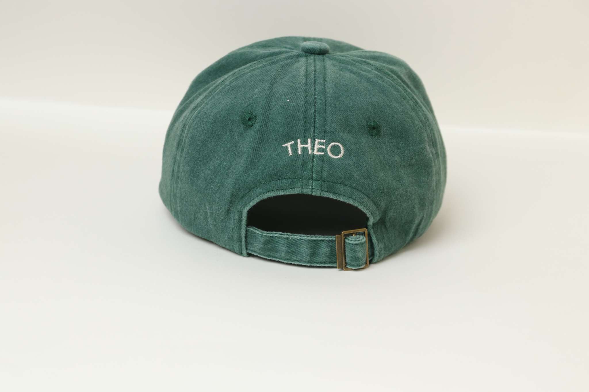 Green personalised hat with embroidered name "THEO" on the back, made of 100% washed cotton.