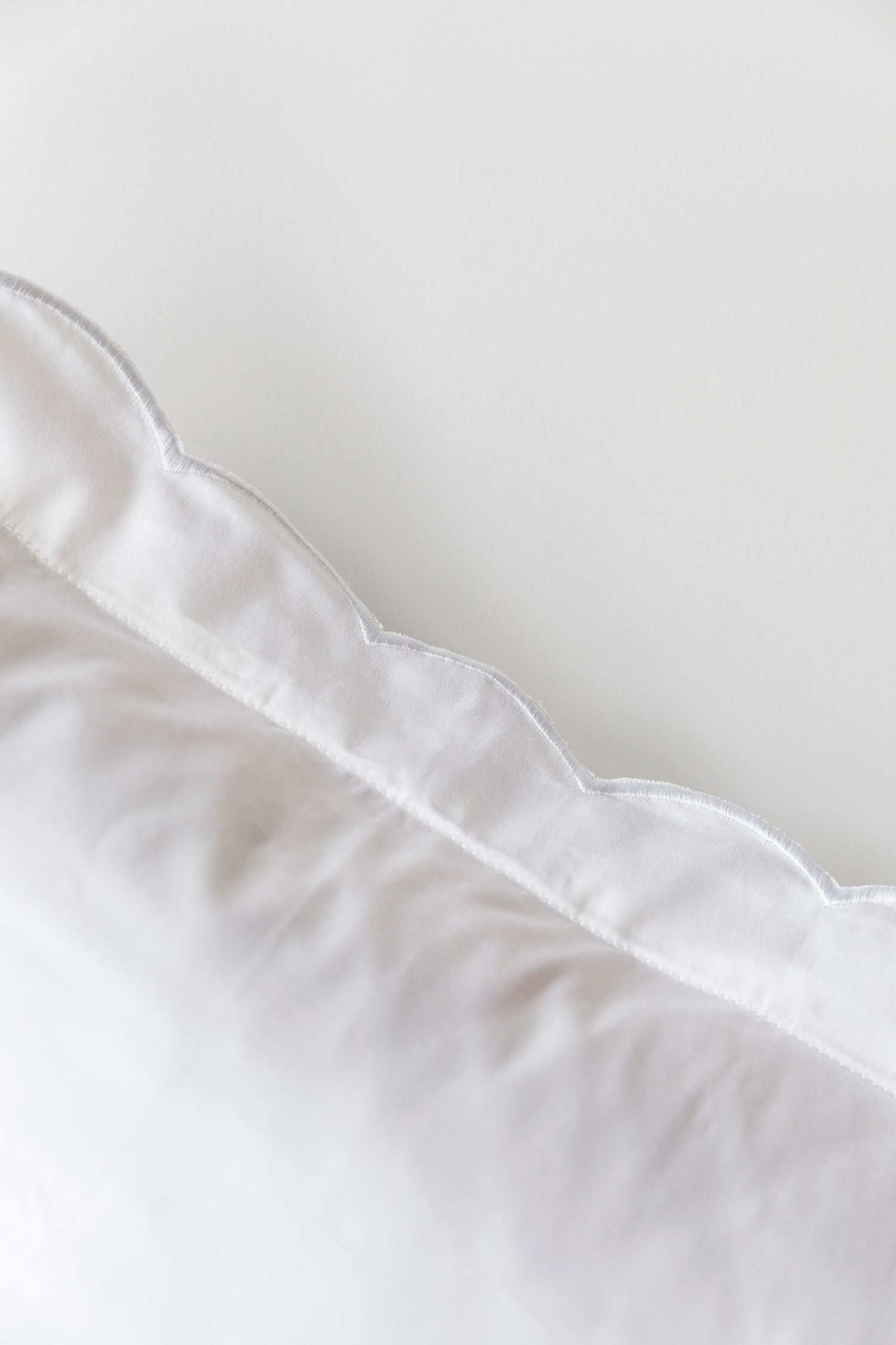 Organic cotton pillowcase with white scalloped edge embroidery.
