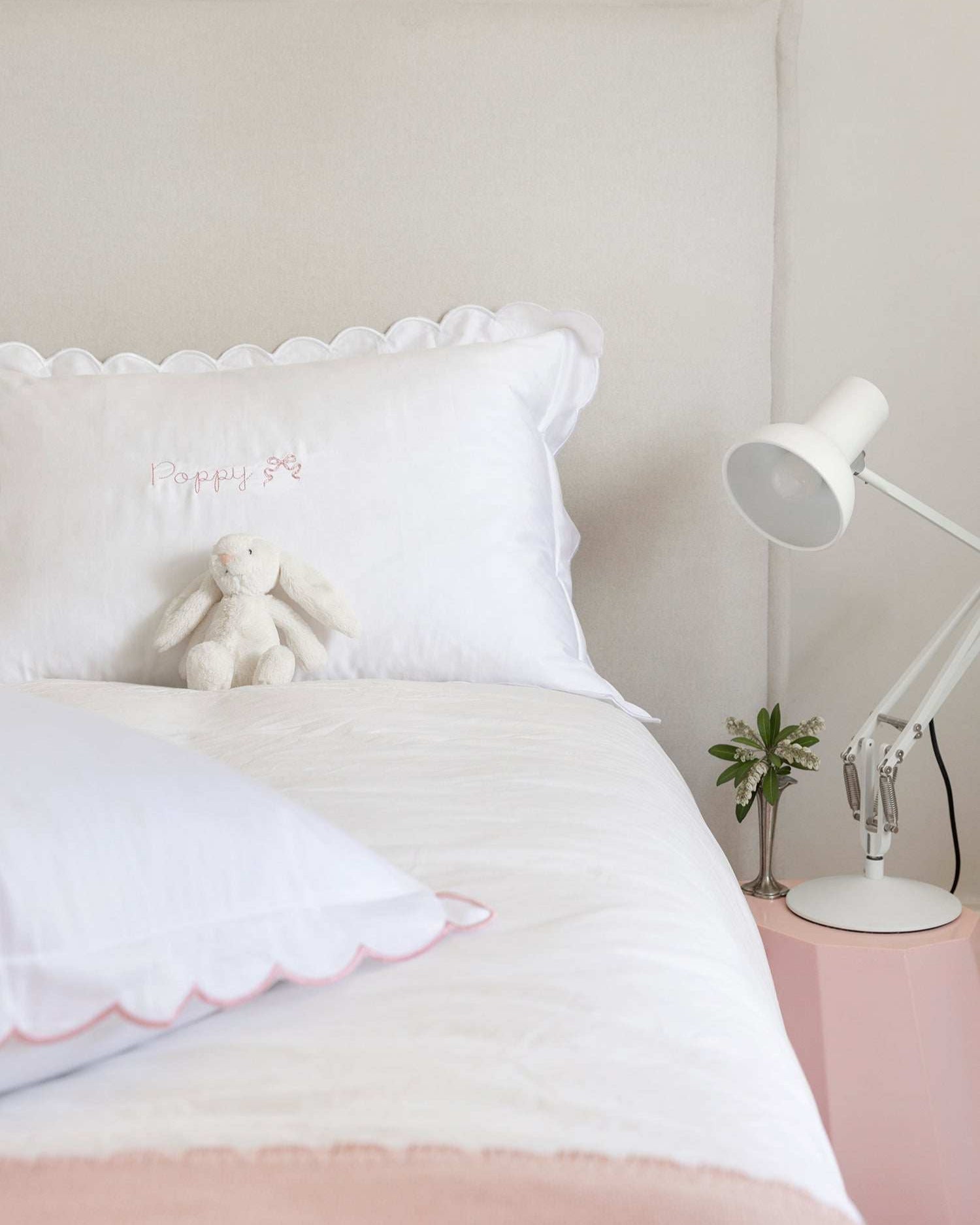 Organic cotton pillowcase with white scalloped edge on a bed.