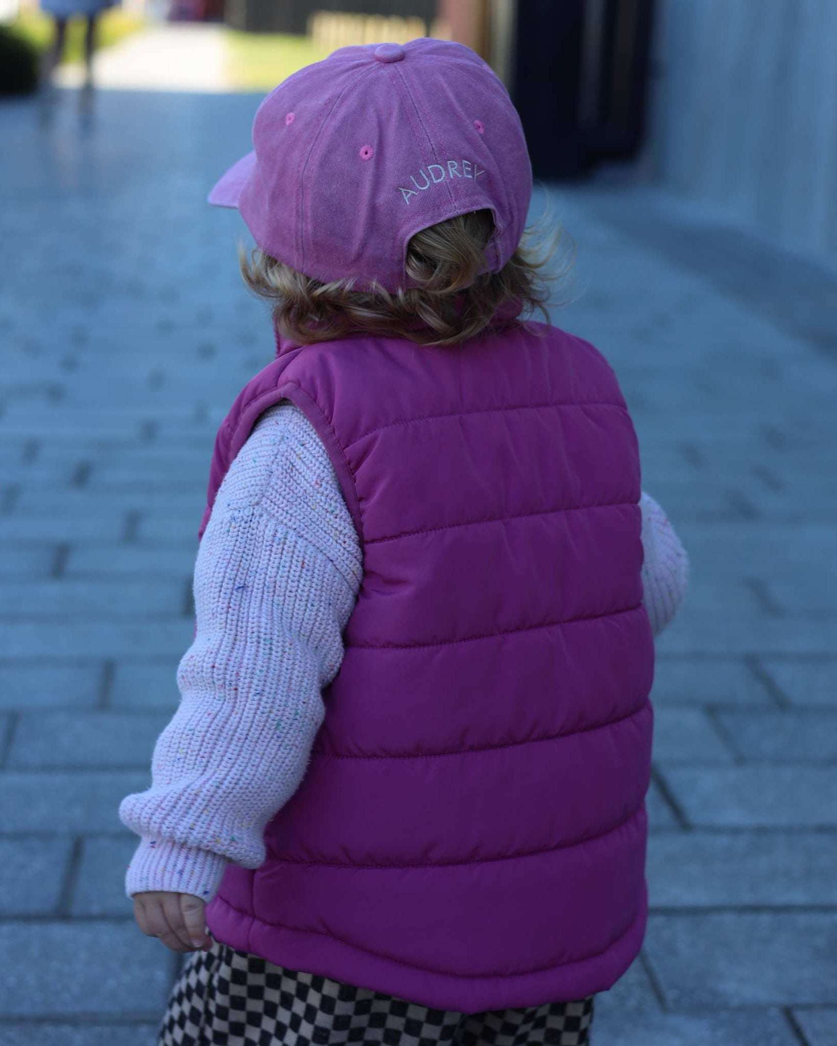 Child wearing a pink Bees Personalised Hat with a custom name embroidered on the back.