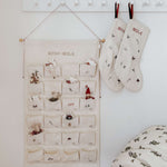 Embroidered Advent Calendar with personalized names, ivory cotton canvas, decorative pockets, and hanging string with tiny bells.