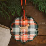 Personalised pet ornament featuring a plaid pattern and embroidered dog design with name "Honey" hanging on a red ribbon in holiday decor setting