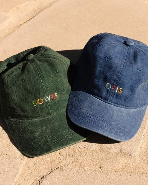 Personalised hat with multi-coloured embroidered text on washed cotton fabric.