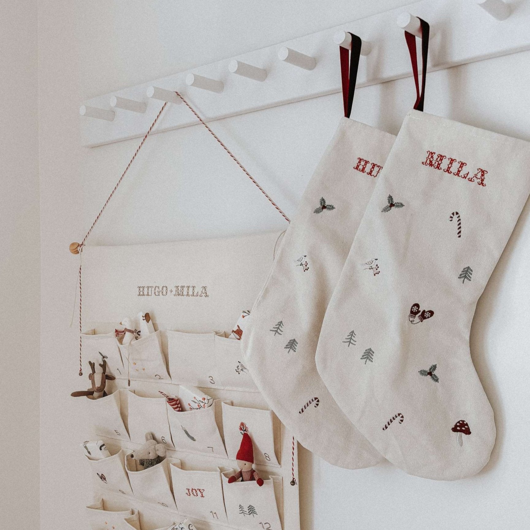 Linen stocking with holiday pattern and personalized names hanging on white hooks