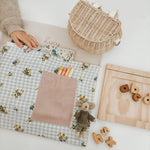 Personalised floral gingham chair bag with crayons and toys on a learning table.