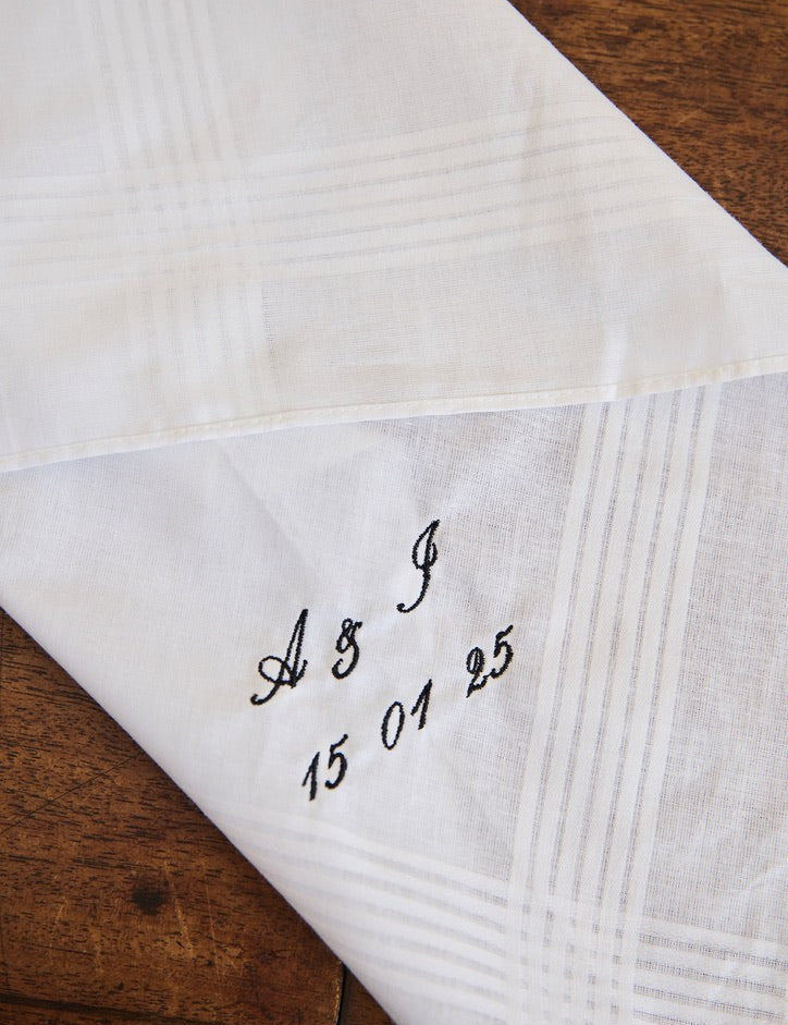 White cotton men's handkerchief with personalized embroidered initials and date on corner