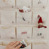 Embroidered Advent Calendar made of ivory cotton canvas with numbered pockets, whimsical embroidery, tiny bells, and personalized options.