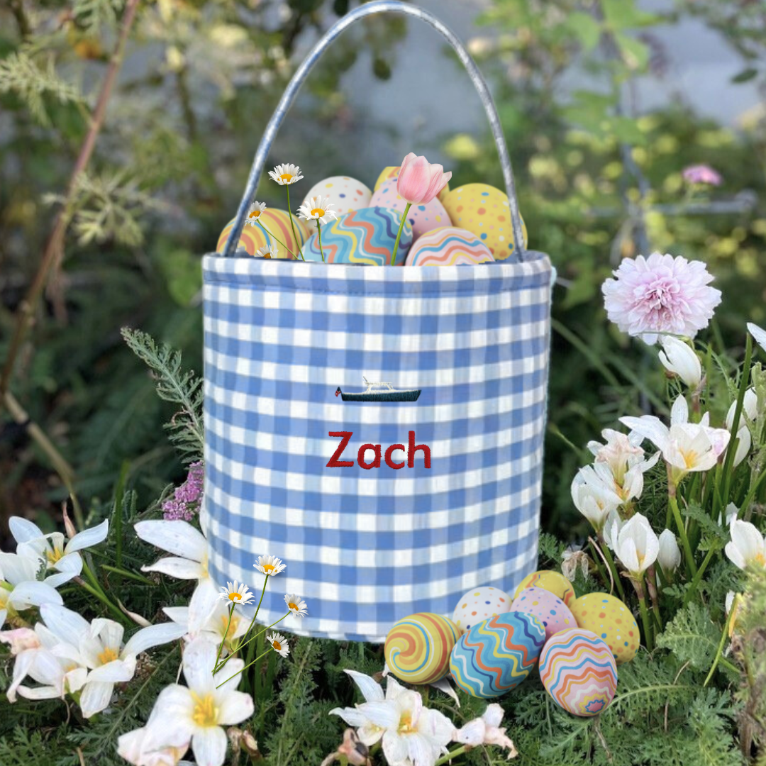 Personalised gingham Easter bucket with embroidery and eggs, surrounded by flowers.