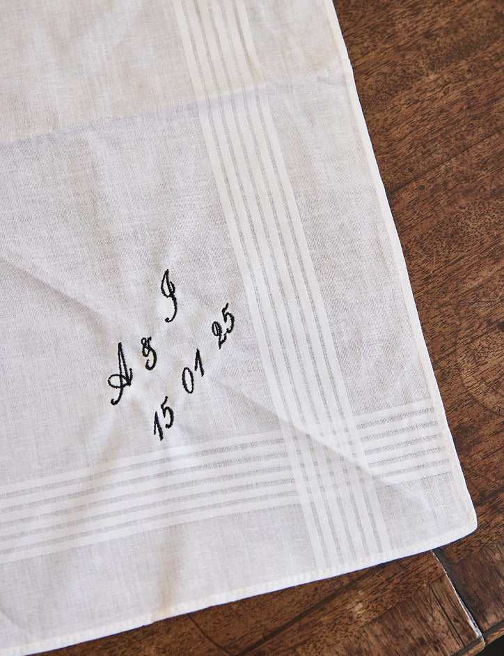Personalized men's white cotton handkerchief embroidered with initials and date on wooden surface