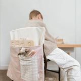 Child sitting with a personalised pink chair bag, ideal for organizing school supplies, made from durable cotton canvas.