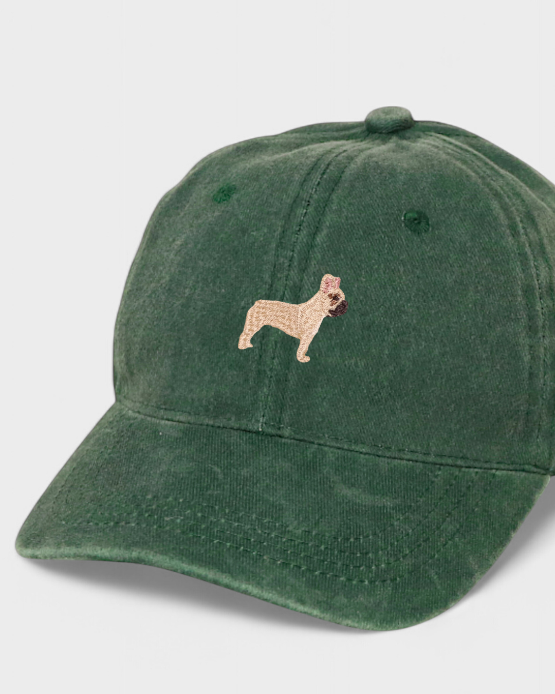 Green baseball cap with embroidered French Bulldog design on front.