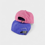 Two Doberman personalised hats in pink and blue washed cotton with custom embroidery on the back, featuring adjustable straps.