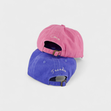 Two Doberman personalised hats in pink and blue washed cotton with custom embroidery on the back, featuring adjustable straps.