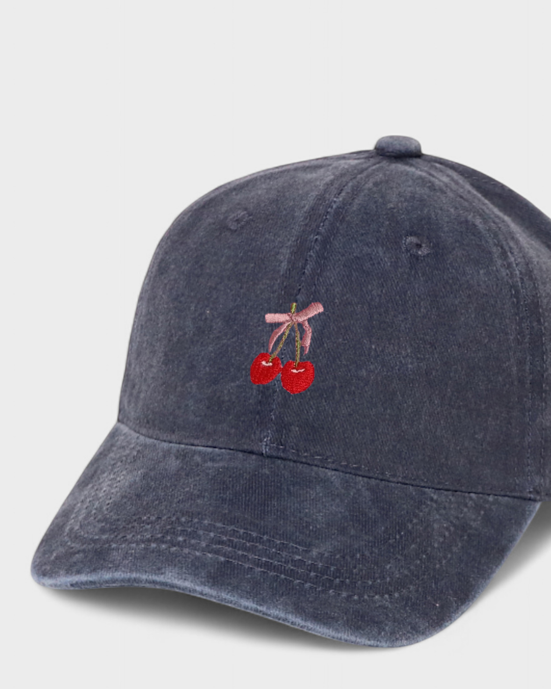 Navy blue personalised hat with embroidered cherries and pink bow on the front.
