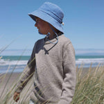 Embroidered blue bucket hat on child at the beach, designed for ages 2-6, made in New Zealand.